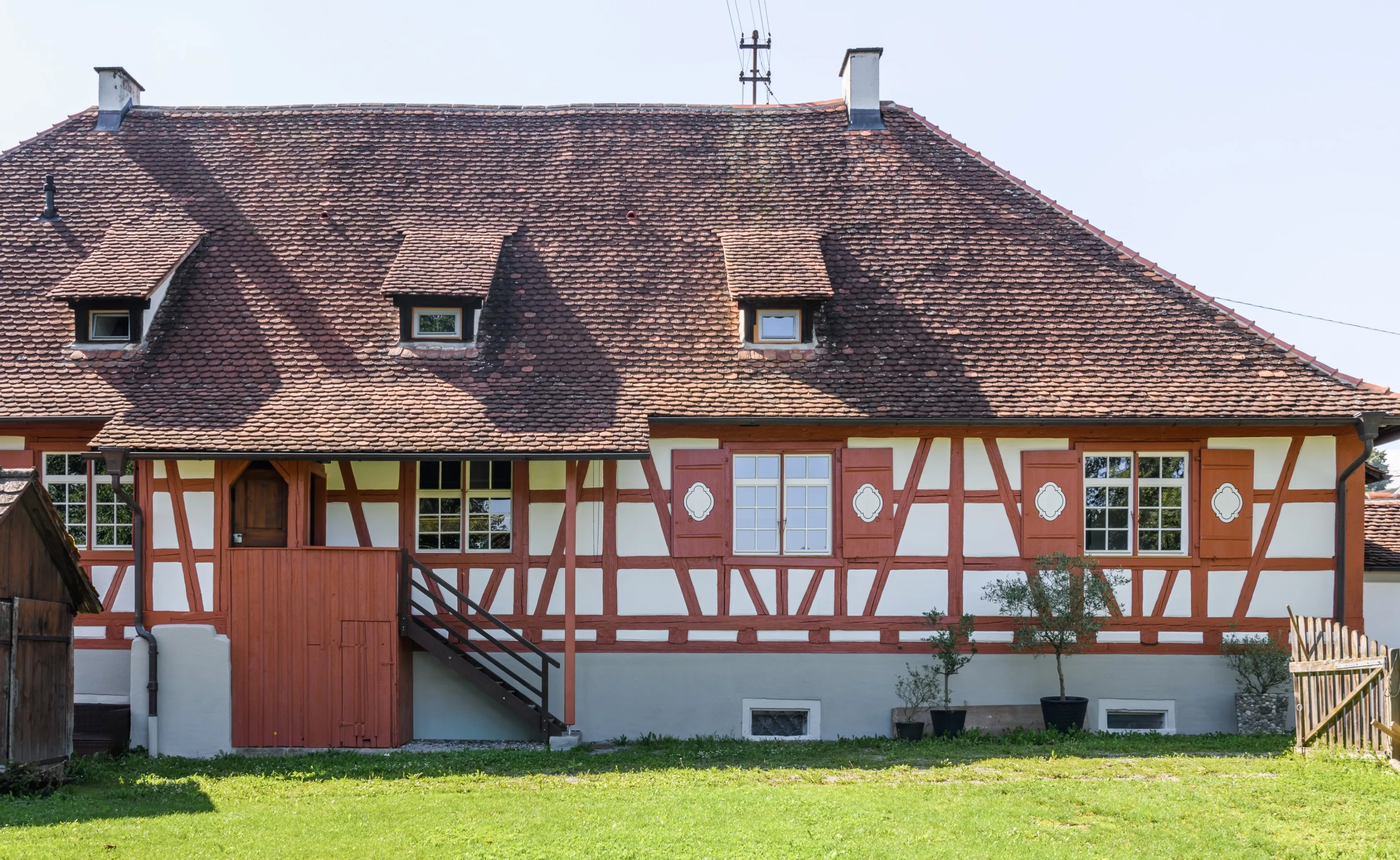Historisches, denkmalgeschütztes Gebäude in Bermatingen mit rotem Fachwerk und weißen Gefachen und Dachdeckung mit Biberschwanzziegel
