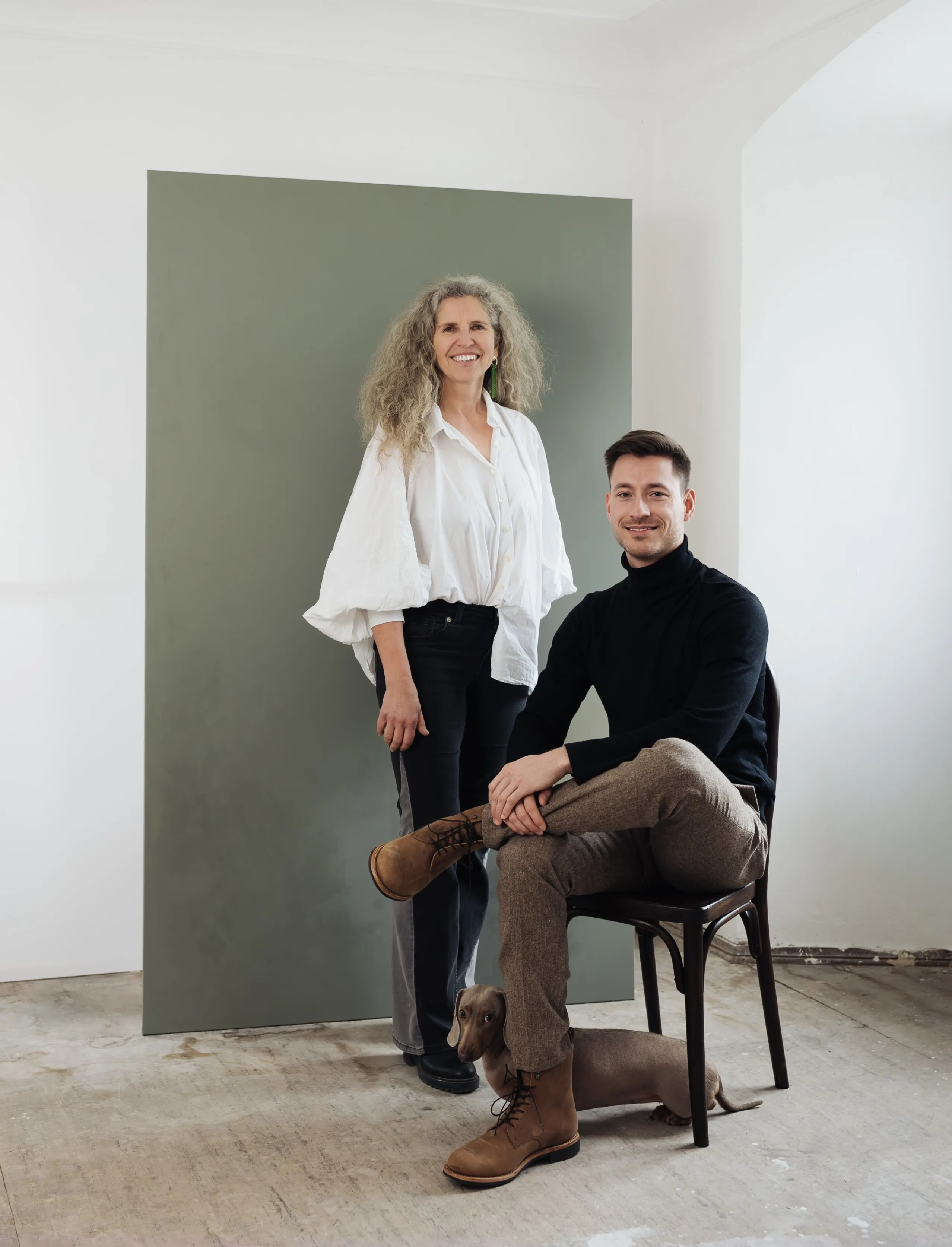 Architektin Corinna Wagner und Architekt Eric Lenz und Dackel Mali vor einer grünen Leinwand in einem Altbau auf der Insel Lindau